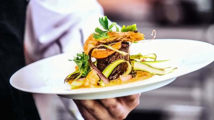 a waiter holding a plate of artfully arranged food, featured image for an article titled 