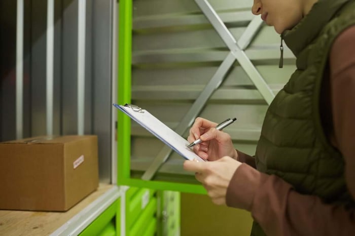 A woman checking an inventory list in front of storage units Calgary