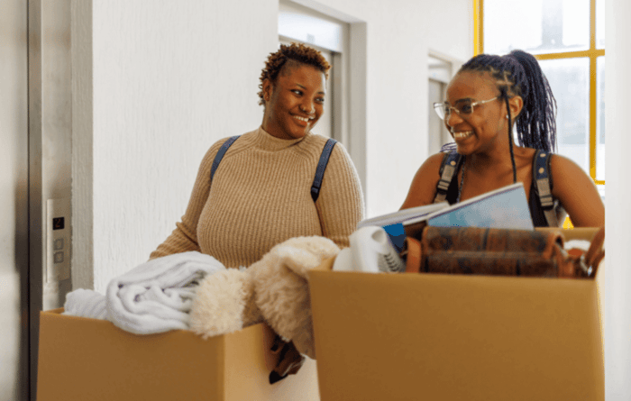 Two college students with moving boxes after taking advantage of back-to-school storage hacks