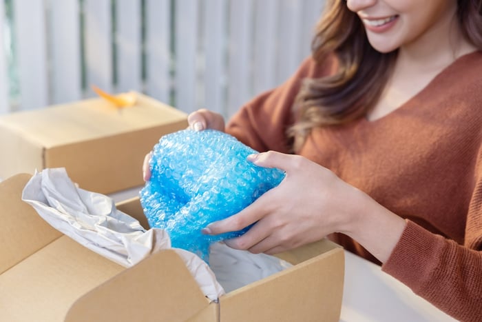 woman wrapping a fragile item for better storage unit organization