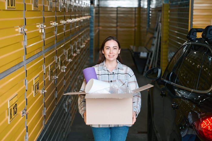 Woman carrying a box at a facility while comparing storage unit costs in El Paso, TX.