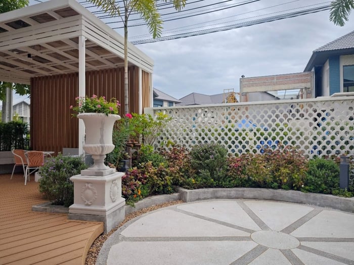 อีกหนึ่งมุมที่โดดเด่น เป็นมุมพักผ่อนที่ร่มรื่นและน่านั่งคือ ศาลาโปร่งหลังคาสีขาว ที่ออกแบบตกแต่งให้เข้ากับสวนและต้นไม้ใหญ่เดิมที่มีอยู่ ทาง Interior Designer เลือกใช้เส้นสายแบบเรียบง่าย