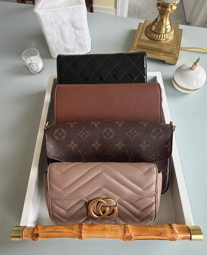 Display Tray of Luxury Clutches with Gucci Crossbody in Front, sitting on a blue desk