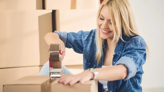 woman taping packing boxes shut