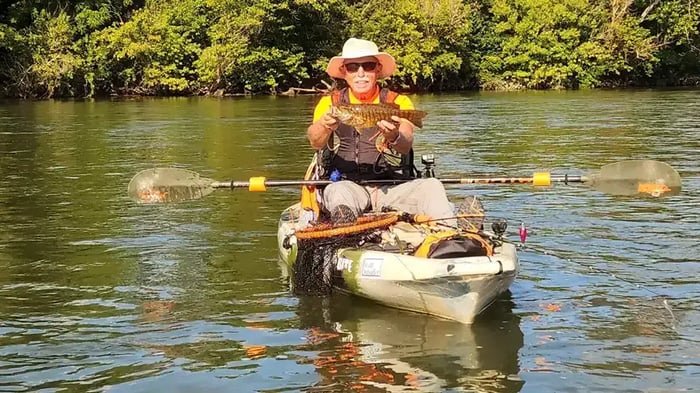 A man holding a fish in his kayak on the Holston River near Mini Mall Storage
