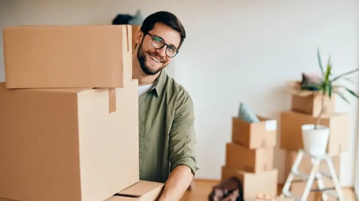 a man holding a stack of moving boxes with more visible in the background