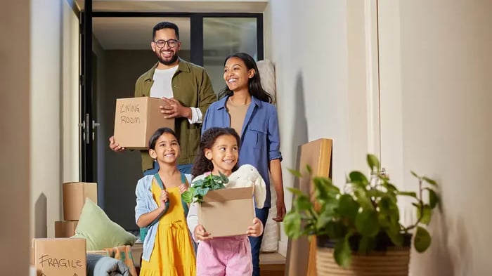 a family of four holding moving boxes