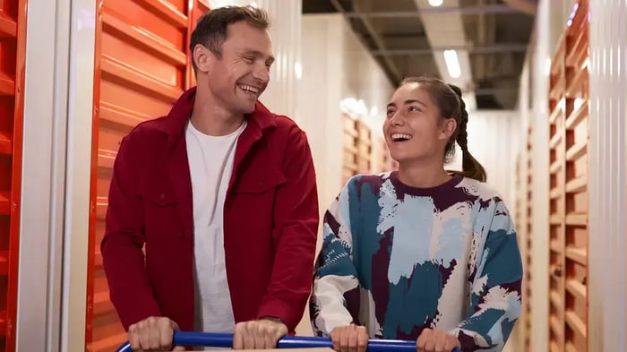 a couple pushing a handcart at a storage facility