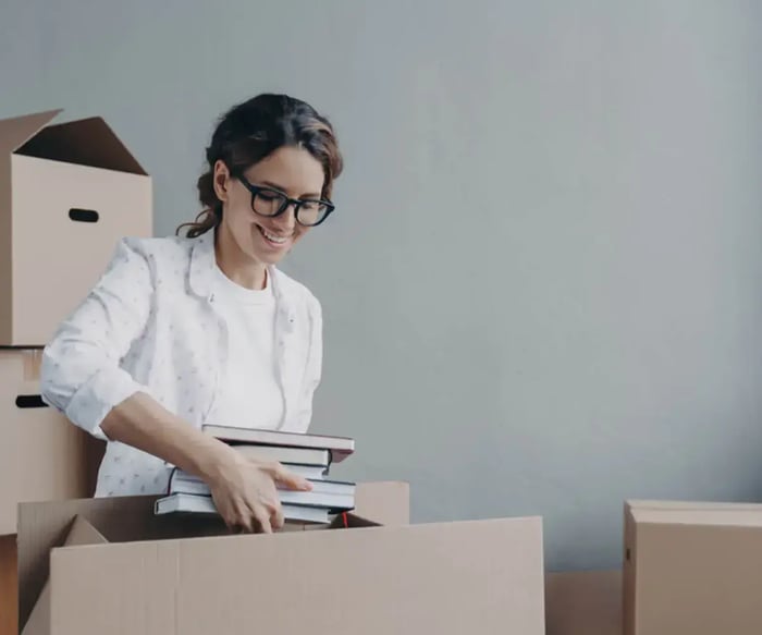 a student storing books in moving boxes