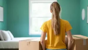 a student with moving boxes in an empty, packed-away dorm room