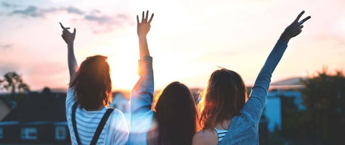 Three girls outside with their hands in the air