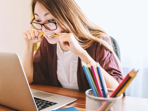 Girl at her computer stressed out, biting her pencil