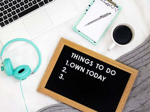 Turquoise headphones, laptop, and leterboard saying things to do today