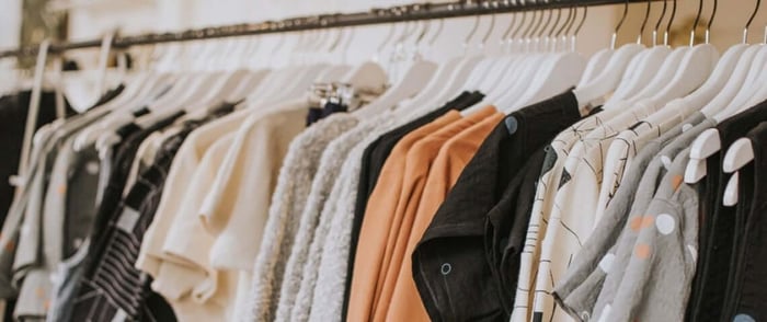 Variety of shirts, sweaters, and other tops on hangers showing a cluttered environment