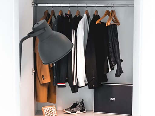 A closet with a dresser and chair inside of it