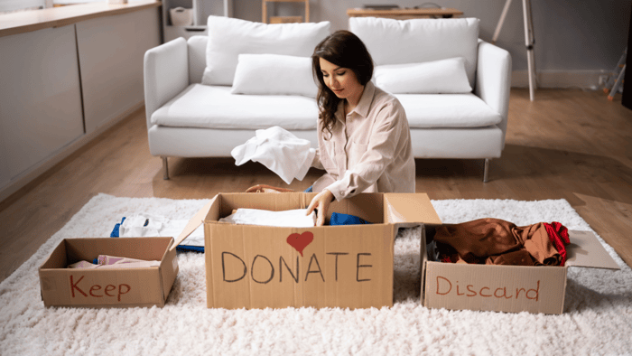 Woman sorting household belongings into a labeled donation box