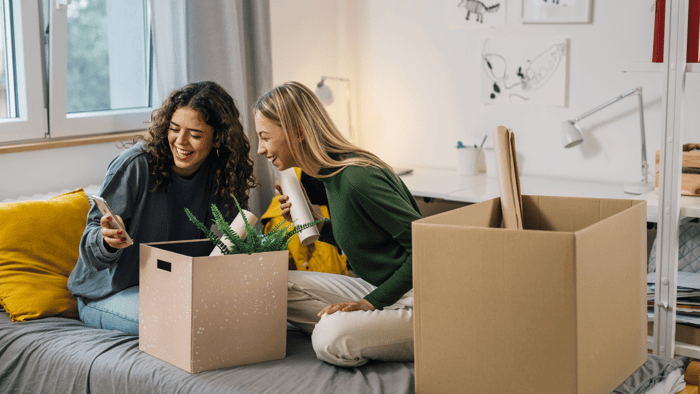 College roommates sorting belongings and packing boxes in a shared apartment