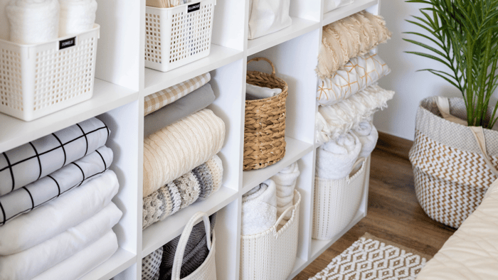 Organized shelving with baskets, folded linens, and labeled storage containers