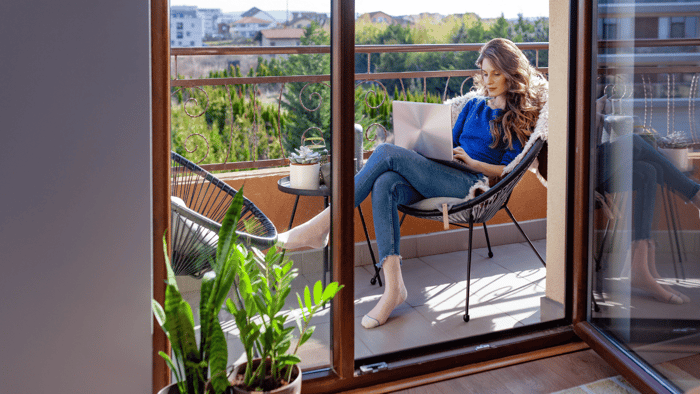 Woman relaxing on a small apartment balcony with compact seating and plants