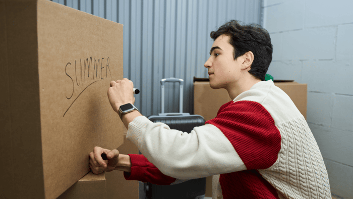 College student carrying a moving box into a self storage unit