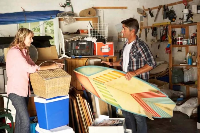A couple laughs and smiles while tidying up garage