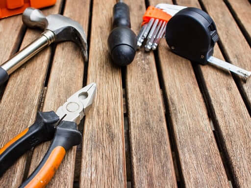 Pliers, hammer and other tools on a wooden surface
