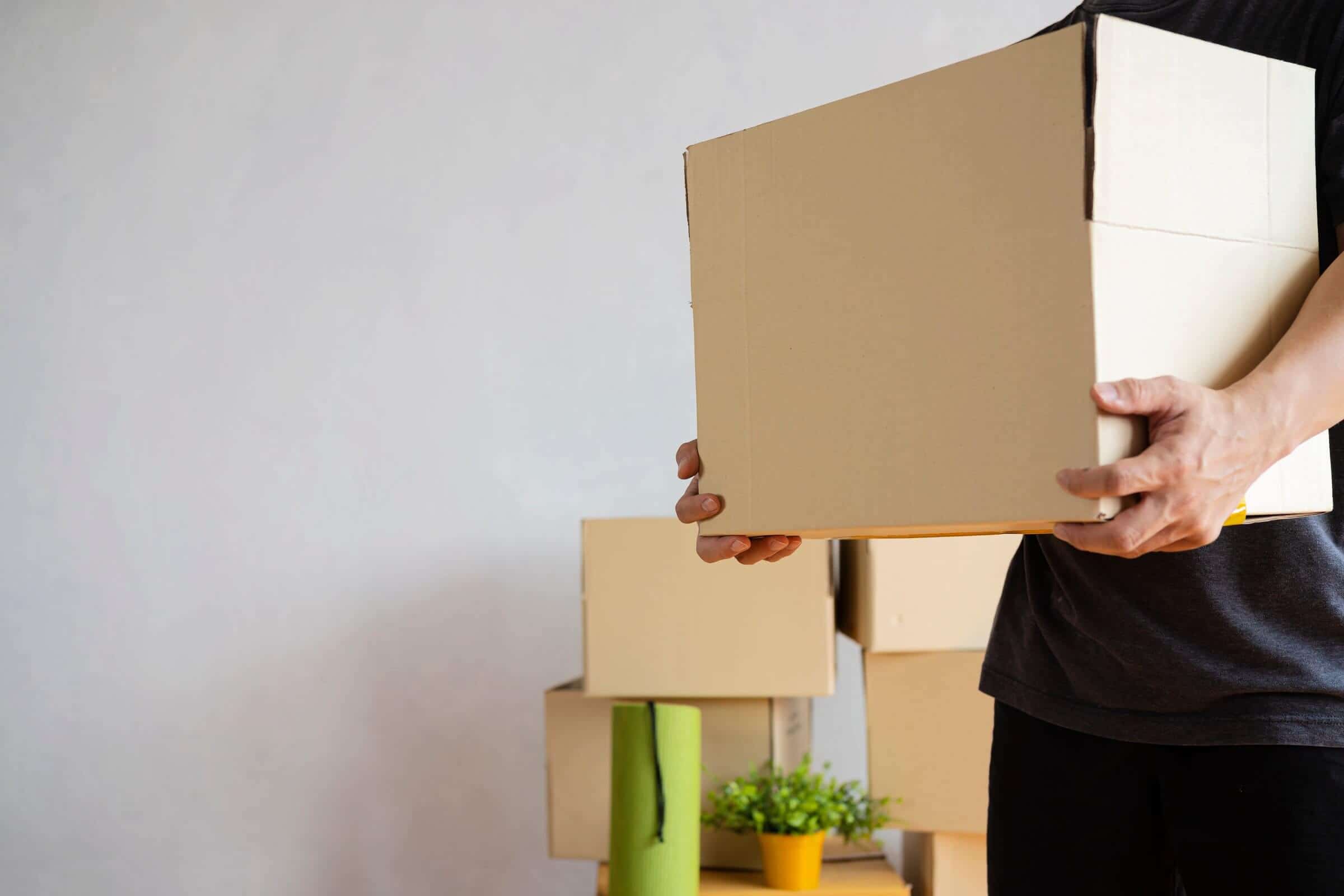 Man holding cardboard box going to storage units in Calgary, Alberta.